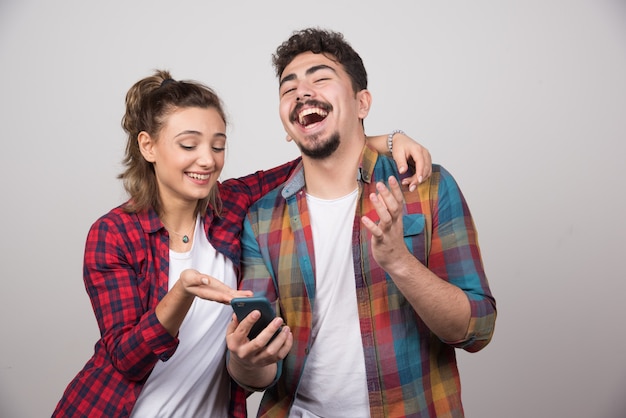 Image of a young woman looking at mobile phone of her man .