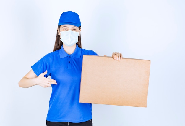 판지 상자를 들고 의료 마스크에 젊은 여자의 이미지.