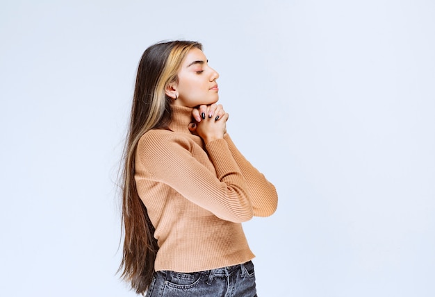 Изображение модели молодой женщины в коричневом свитере стоя и позирует.