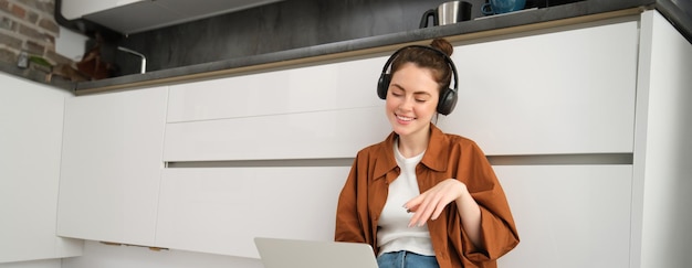 Free photo image of young woman programmer freelancer working form home sitting in headphones and using laptop