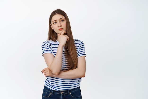 Image of young woman thinking, looking right with serious thoughtful face expression, white background