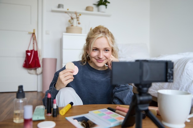 image of young woman vlogger records video on digital camera shows beauty products recommending