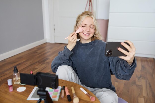 Free photo image of young woman vlogger taking selfie in her room talking to her followers during online live