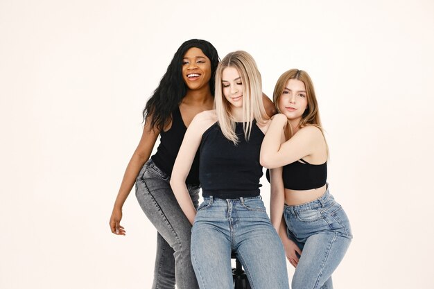 Image of a young women. Multiracial friends posing isolated over white wall background.