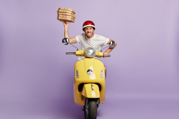 Impatient deliveryman driving scooter while holding pizza boxes