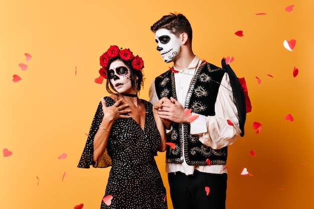 Free photo impatient mexican girl in traditional dress, listening to words of love from her young man. portrait of cute couple