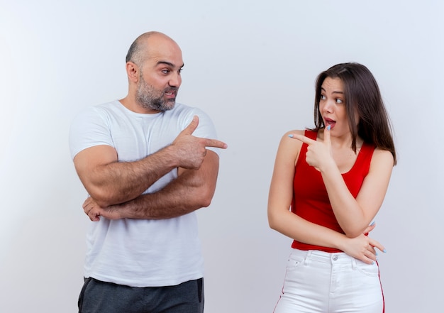 Impressed adult couple looking at each other and doing pistol gesture 