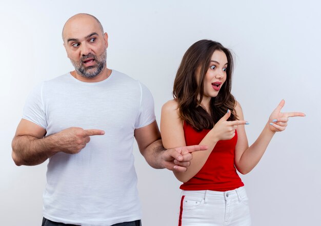 Impressed adult couple looking and pointing at side 