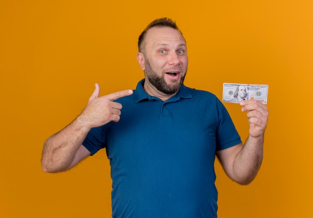 Free photo impressed adult slavic man holding and pointing at dollar