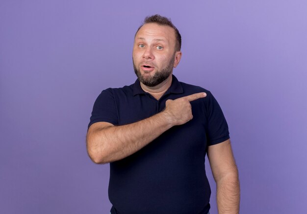 Impressed adult slavic man pointing at side isolated