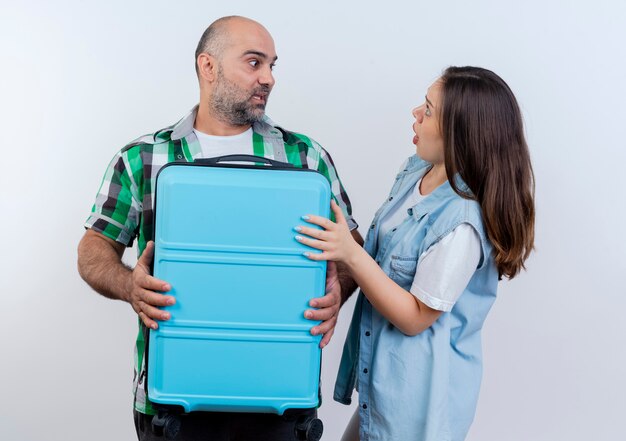 Impressed adult traveler couple man holding suitcase and woman putting hand on suitcase both looking at each other 