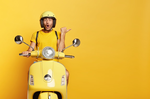 Впечатлен парень в шлеме за рулем желтого скутера
