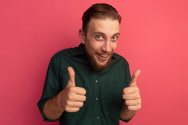 Impressed handsome blonde man thumbs up of two hands isolated on pink wall