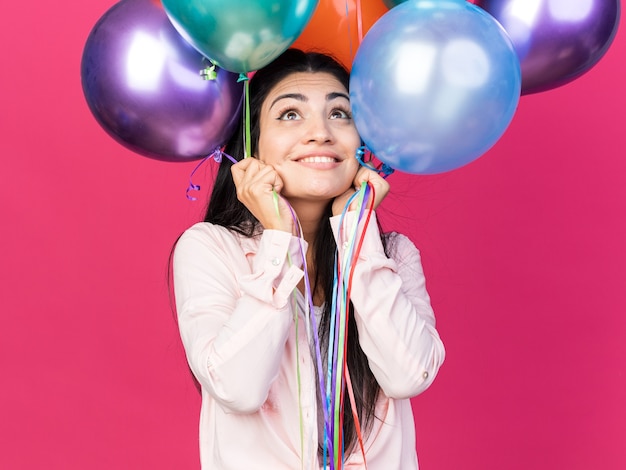 Impressed looking up young beautiful girl holding balloons 