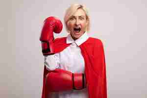 無料写真 空中で拳を叫び続けているボクシンググローブを身に着けている赤いマントの感銘を受けた中年の金髪のスーパーヒーローの女性