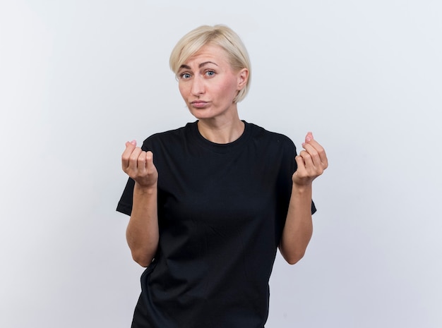 Impressed middle-aged blonde woman looking at front doing tip gesture isolated on white wall