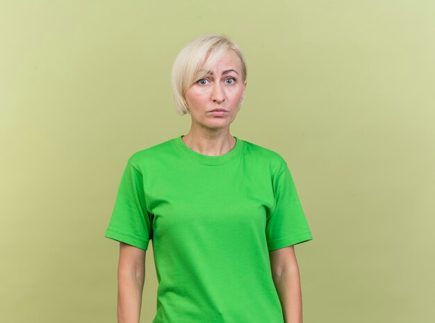 Impressed middle-aged blonde woman looking at front isolated on olive green wall