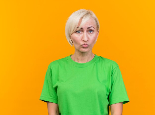 Impressed middle-aged blonde woman looking at front isolated on yellow wall