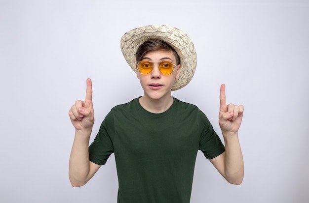 Impressed points at up young handsome guy wearing hat with glasses 