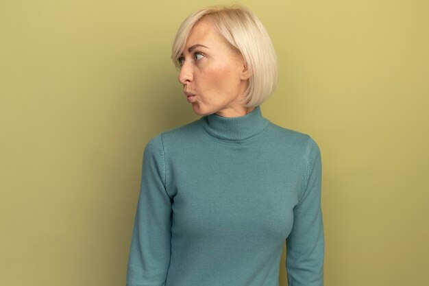 Foto gratuita la donna slava abbastanza bionda impressionata guarda a lato su verde oliva