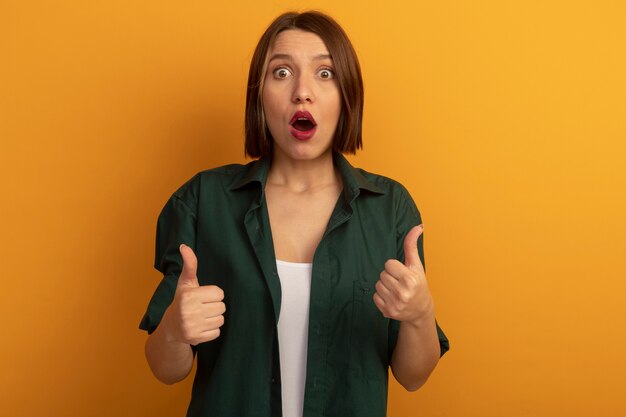 Impressed pretty caucasian woman thumbs up of two hands on orange