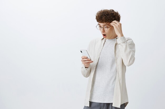 Impressed and shocked teenage guy posing against the white wall