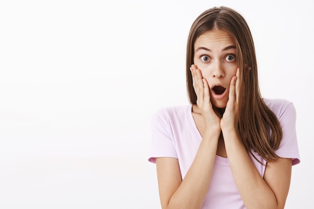 Free photo impressed speechless and amazed gorgeous woman with brown long hair dropping jaw holding palms on face and staring learning outstanding news