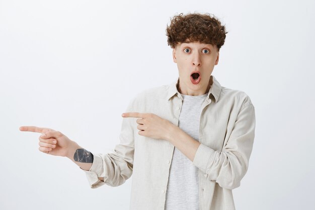 Impressed and surprised teenage guy posing against the white wall