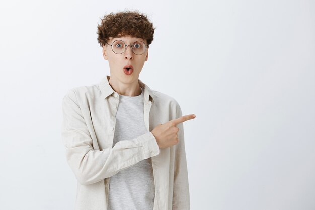 Impressed and surprised teenage guy posing against the white wall