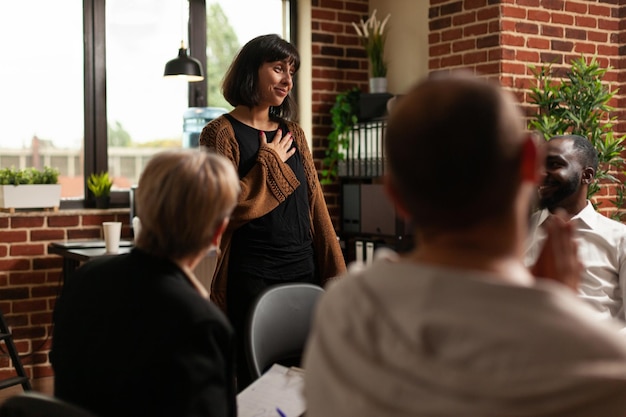 Impressed woman receiving applause from group of people at aa meeting program. Therapy session patients clapping hands and celebrating achievement, showing support to joyful person.