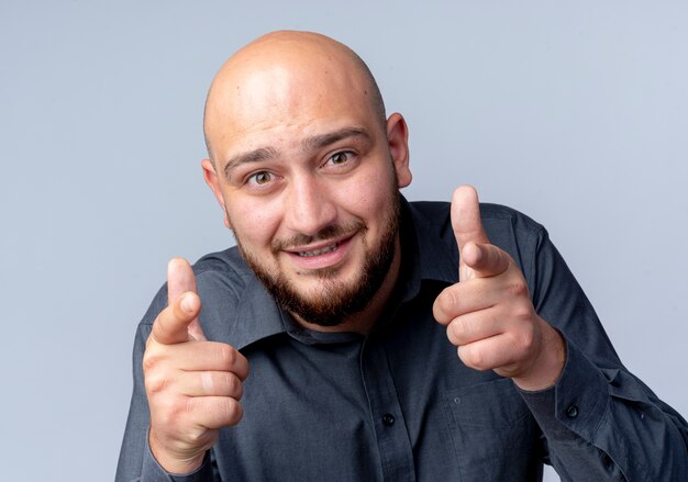 Impressed young bald call center man looking and pointing isolated on white 