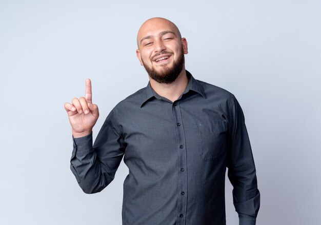 Impressed young bald call center man pointing up isolated on white 