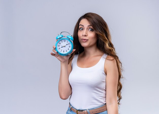 Impressed young beautiful girl holding alarm clock  with copy space