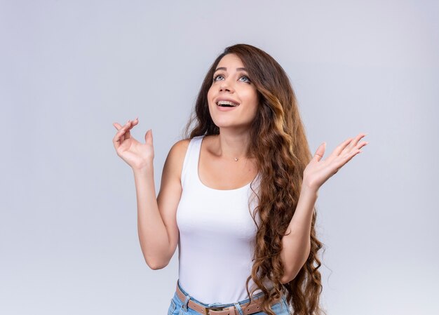 Impressed young beautiful girl looking up with open arms  with copy space