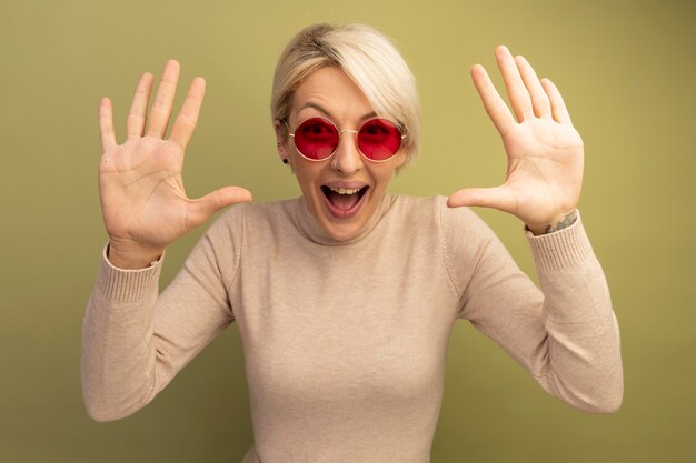 Free photo impressed young blonde girl wearing sunglasses showing empty hands