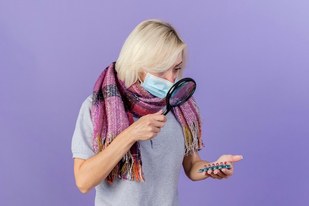 Impressed young blonde ill slavic woman wearing medical mask and scarf