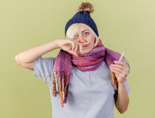 Impressed young blonde ill slavic woman wearing winter hat