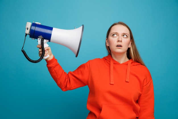 Free photo impressed young blonde woman holding speaker looking up