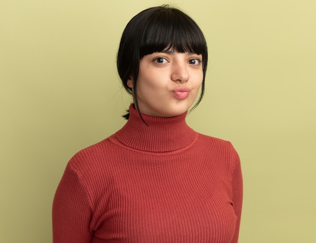 Free photo impressed young brunette caucasian girl looks at camera on olive green