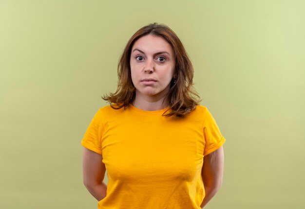 Impressed young casual woman with hands behind her back on isolated green space with copy space