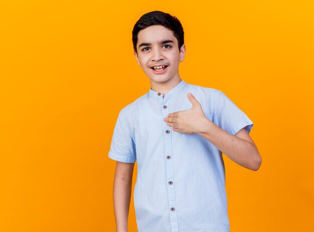 Впечатленный молодой кавказский мальчик, смотрящий на камеру, трогательно сундук, изолированный на оранжевом фоне с копией пространства
