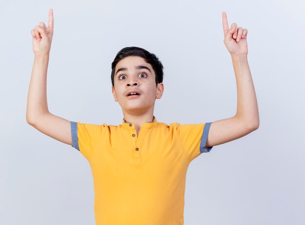 Impressed young caucasian boy looking straight pointing up isolated on white background