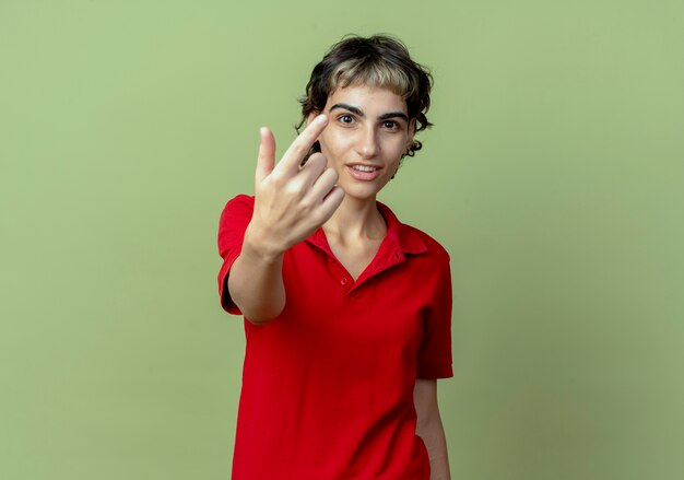 Впечатленная молодая кавказская девушка со стрижкой пикси делает жест на камеру на оливково-зеленом фоне с копией пространства