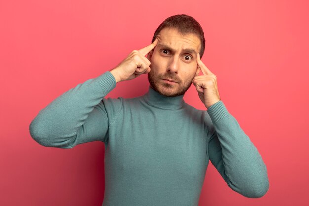 Impressed young caucasian man looking at camera doing think gesture isolated on crimson background