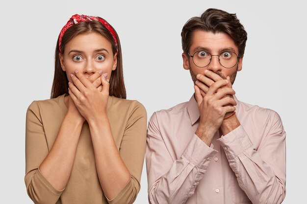 Impressed young couple posing against the white wall