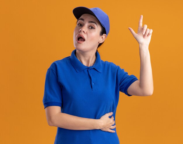 Foto gratuita colpita giovane donna delle consegne in uniforme e berretto rivolto verso l'alto