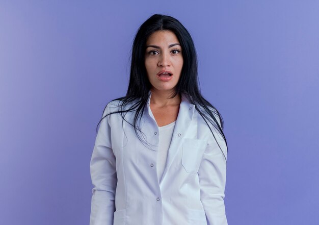 Impressed young female doctor wearing medical robe looking 