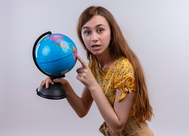 Impressed young girl holding globe and pointing at it on isolated white space