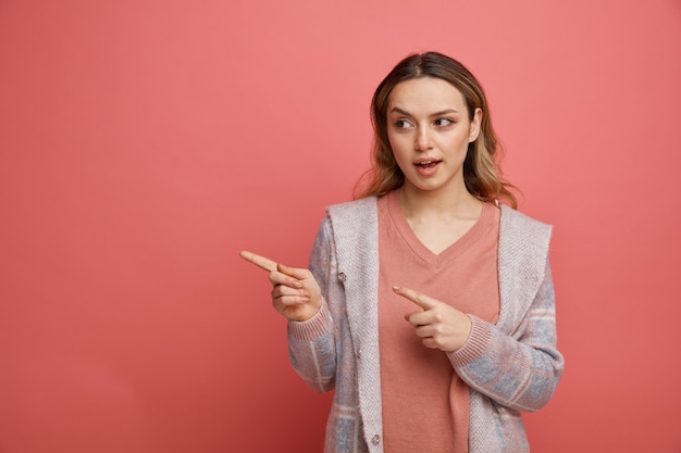 Impressed young girl looking and pointing at side 