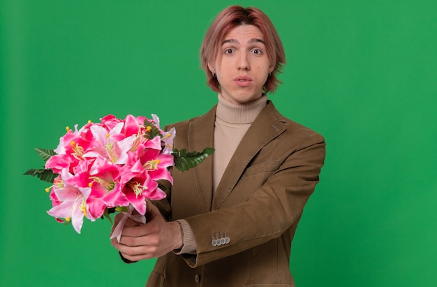 Foto gratuita impressionato giovane bell'uomo che porge un mazzo di fiori guardando